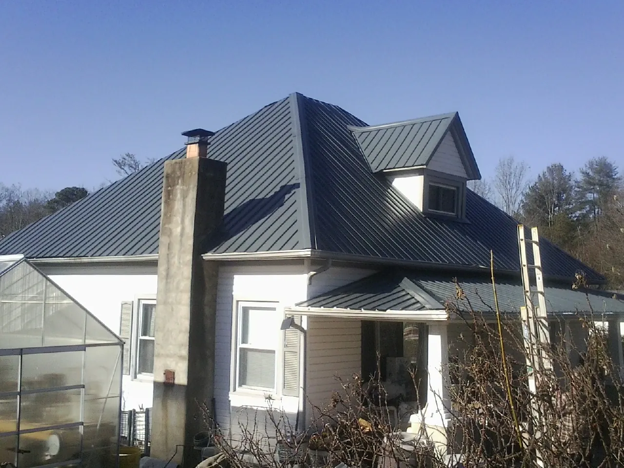 Dark blue standing seam metal roof on a white farmhouse with dormer — Slate & Tile Roof Repair by Roofing Brothers in Fort Deposit