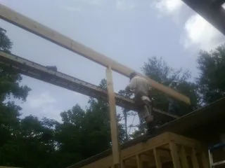 Carpenter setting a ridge beam over a new addition frame — Ice Dam Removal by Roofing Brothers in Fort Deposit