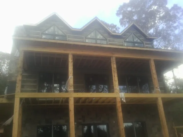 Dormers and porch framing on a large log home under construction — Roof Coating work by our crew in Fort Deposit