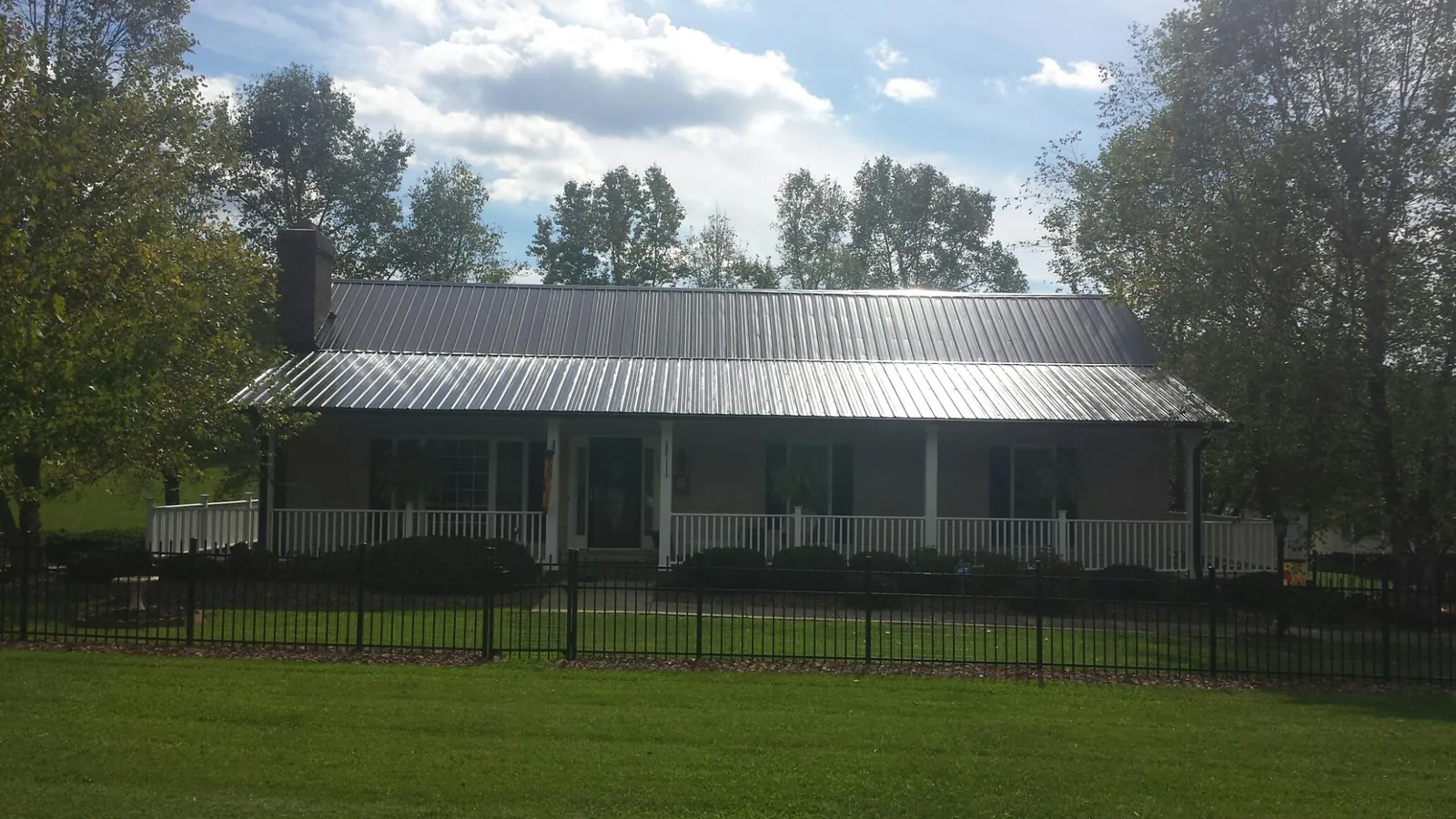 Gray metal roof on a brick ranch with a full width front porch — Gutter Guard Installation work by our crew in Fort Deposit