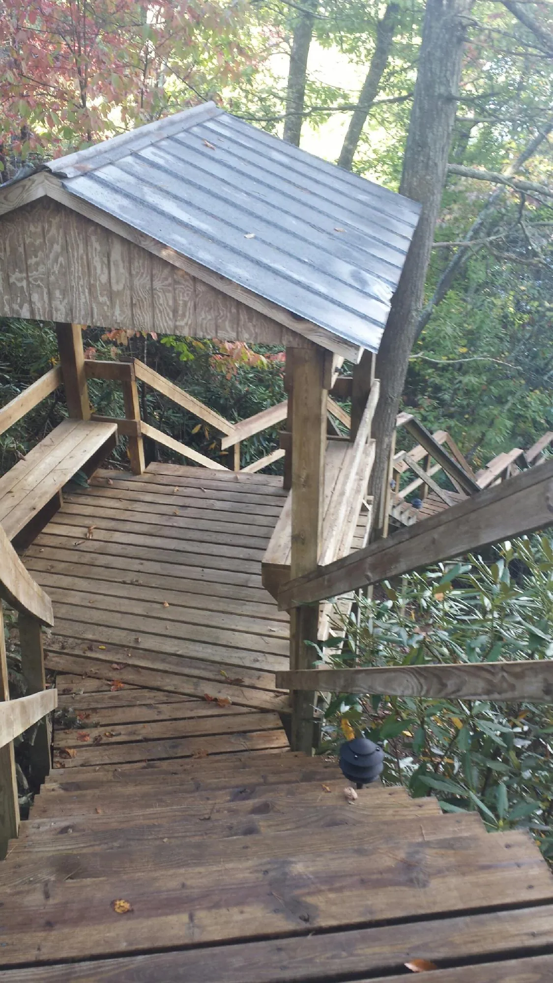 Metal roofed shelter over wooden steps on a wooded walkway — Skylight Repair & Installation work by our crew in Fort Deposit