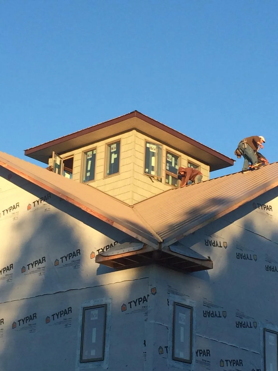 Roofers working around a rooftop cupola on a new metal roof at sunset — Roof Waterproofing in Fort Deposit by Roofing Brothers